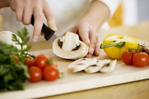 Showing hands cutting a mushroom with tomatoes and peppers displayed