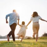 photo of family running playfully, with parents holding the child's hands in between them