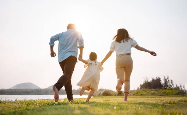 photo of family running playfully, with parents holding the child's hands in between them