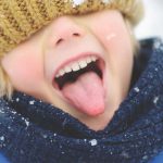 photo of young child trying to catch falling snow on their tongue