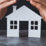 photo of human hands covering a cutout of a house