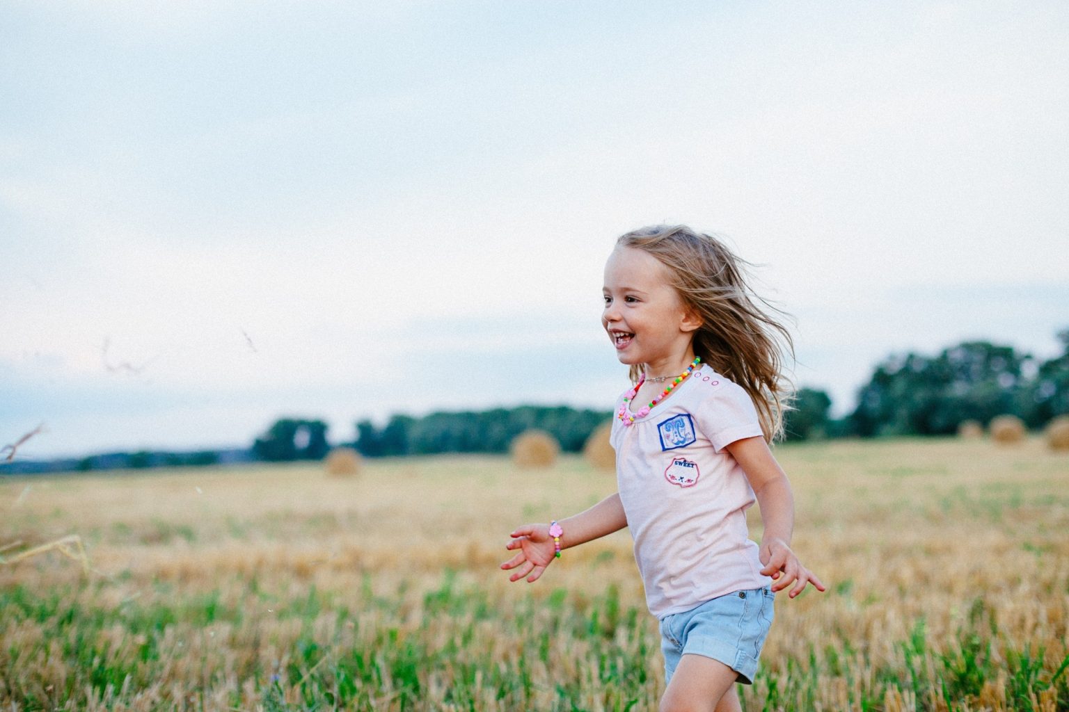 young girl playing in a field and smiling