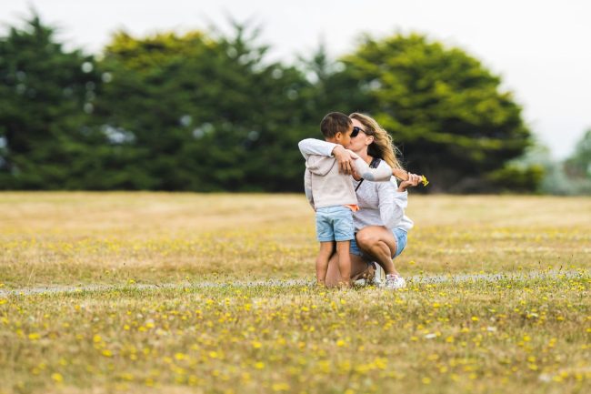 mother embracing young son in an open field
